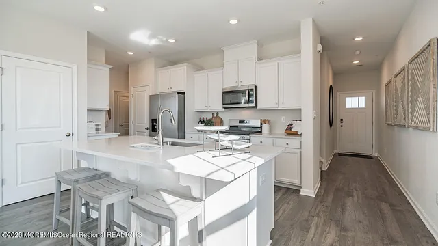 a large kitchen with kitchen island white cabinets and stainless steel appliances
