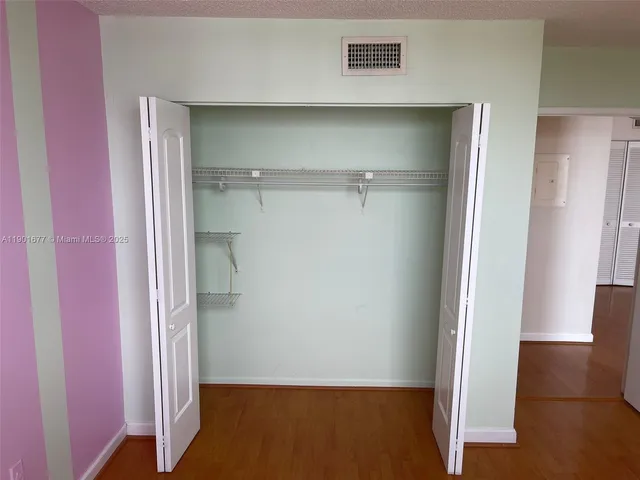 an empty room with wooden floor and entrance