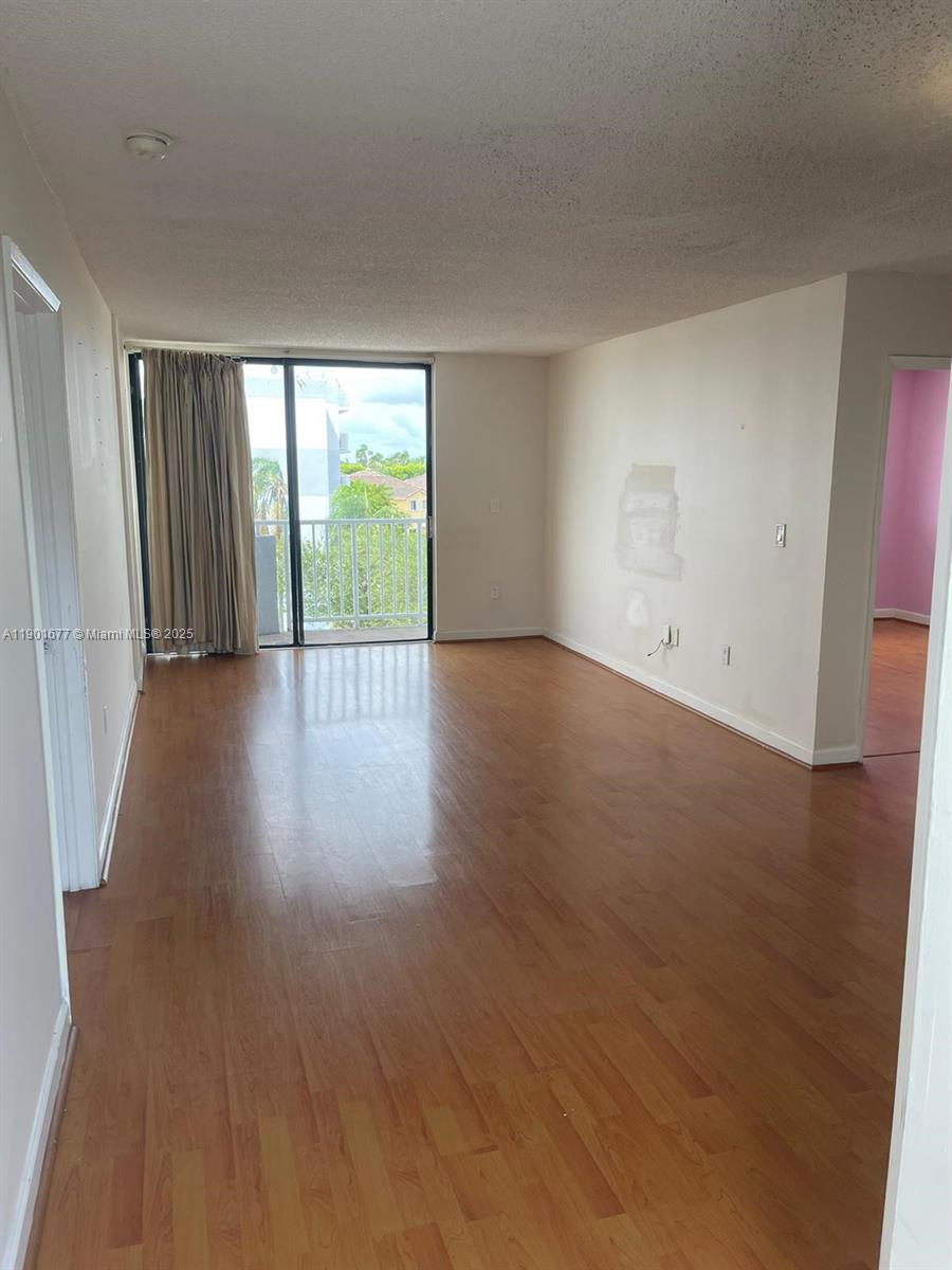 8251 Northwest 8th Street, Unit 414 Miami, FL 33126 - Photo 5 of 25 a view of an empty room with wooden floor and a window