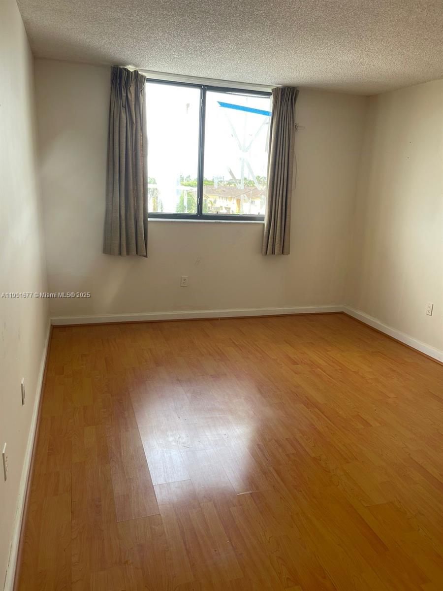 8251 Northwest 8th Street, Unit 414 Miami, FL 33126 - Photo 7 of 25 an empty room with wooden floor and windows