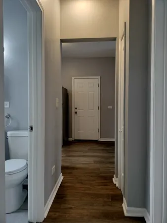 a view of a hallway with wooden floor and a bathroom