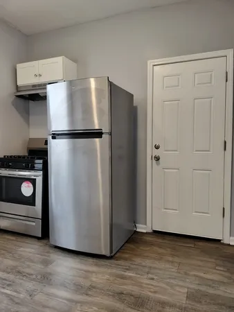a view of a refrigerator in kitchen and an empty room