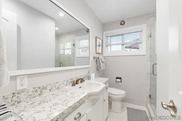 a bathroom with a granite countertop sink a toilet and a mirror