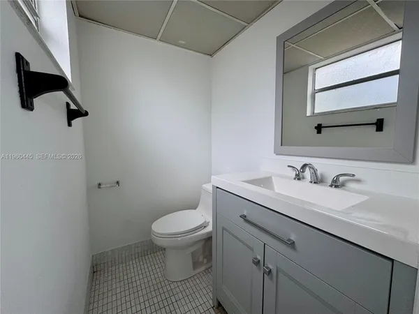 a bathroom with a granite countertop sink toilet and mirror