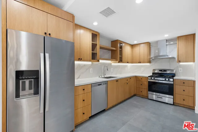 a kitchen with stainless steel appliances granite countertop a refrigerator a sink and a stove