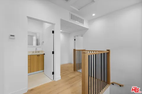 a view of a hallway with wooden floor and a bathroom