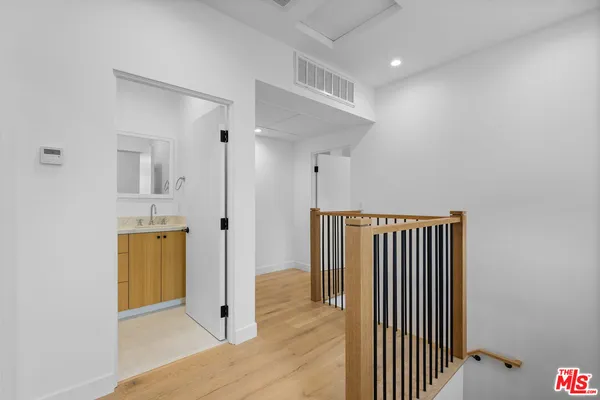 a view of a hallway with wooden floor and a bathroom
