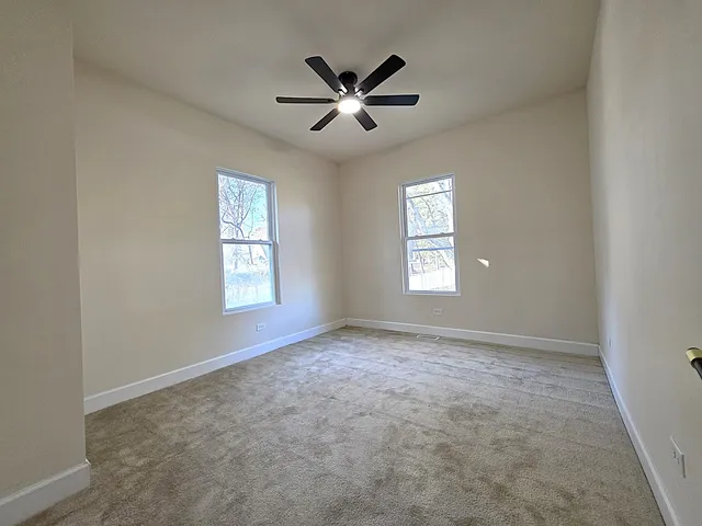 an empty room with windows and ceiling fan