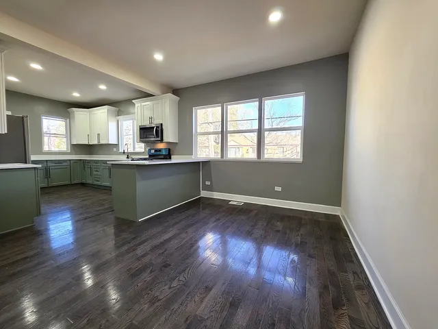 an open kitchen with wooden floor and white cabinets