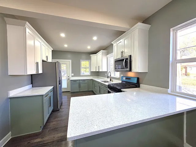 a large kitchen with stainless steel appliances granite countertop a sink a stove and a refrigerator