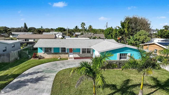 a aerial view of a house next to a big yard and large trees