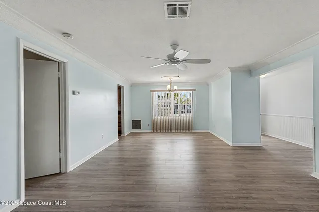 a view of an empty room with window and wooden floor