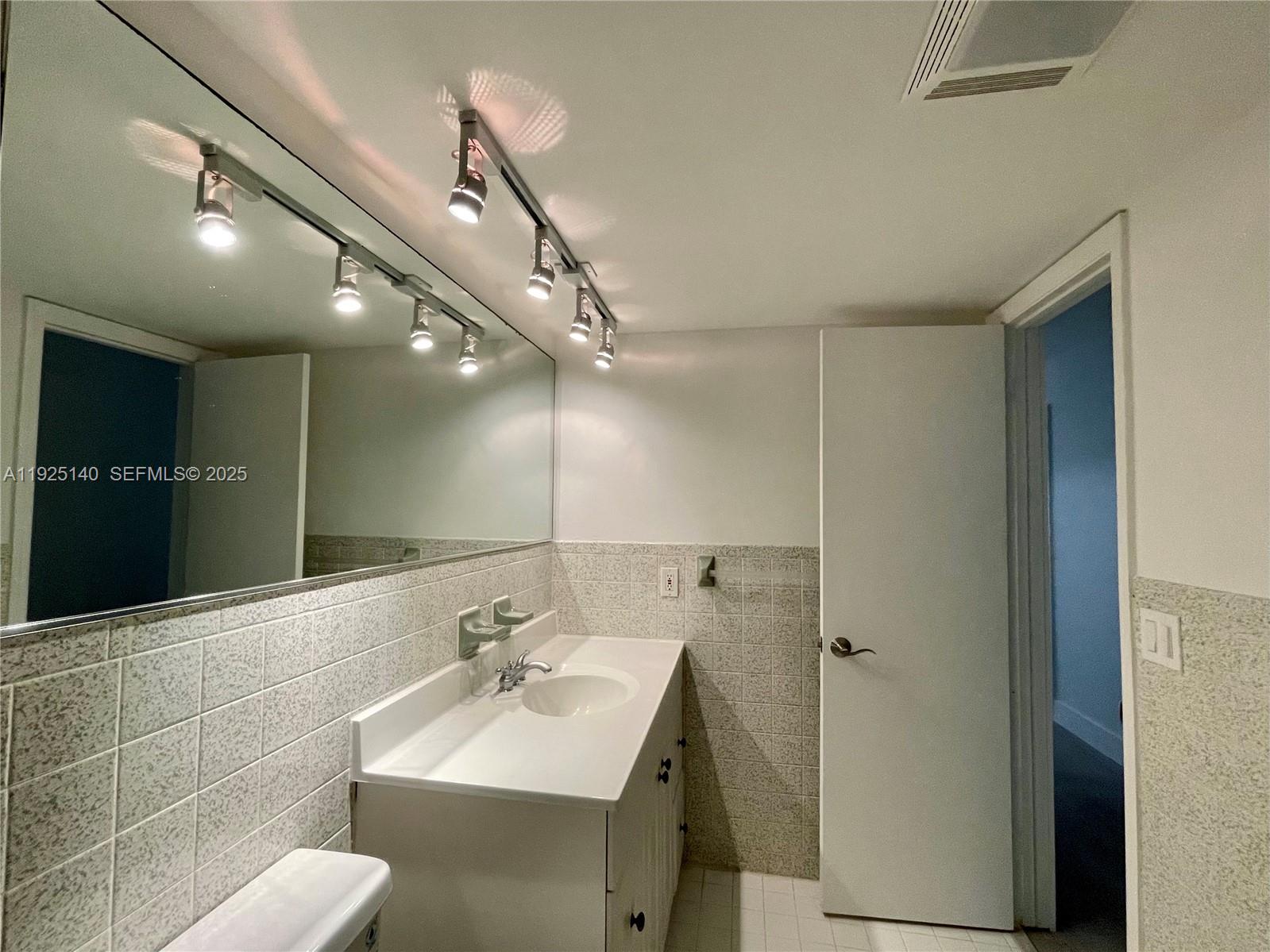 2230 Spanish Trail, Unit A Delray Beach, FL 33483 - Photo 12 of 23 a bathroom with a sink a toilet and a mirror