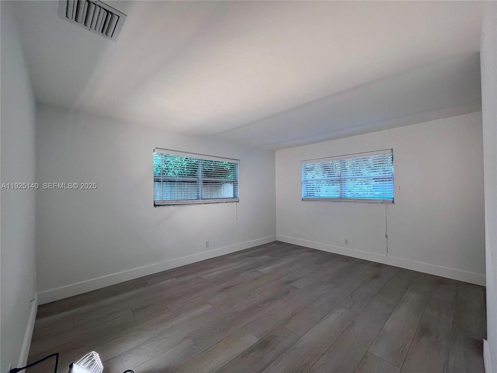 2230 Spanish Trail, Unit A Delray Beach, FL 33483 - Photo 15 of 23 an empty room with wooden floor and windows