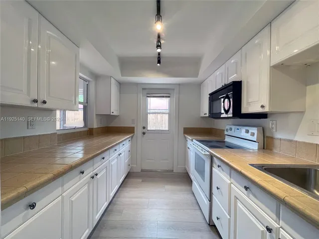 a large kitchen with stainless steel appliances granite countertop a sink a stove top oven a counter space and cabinets