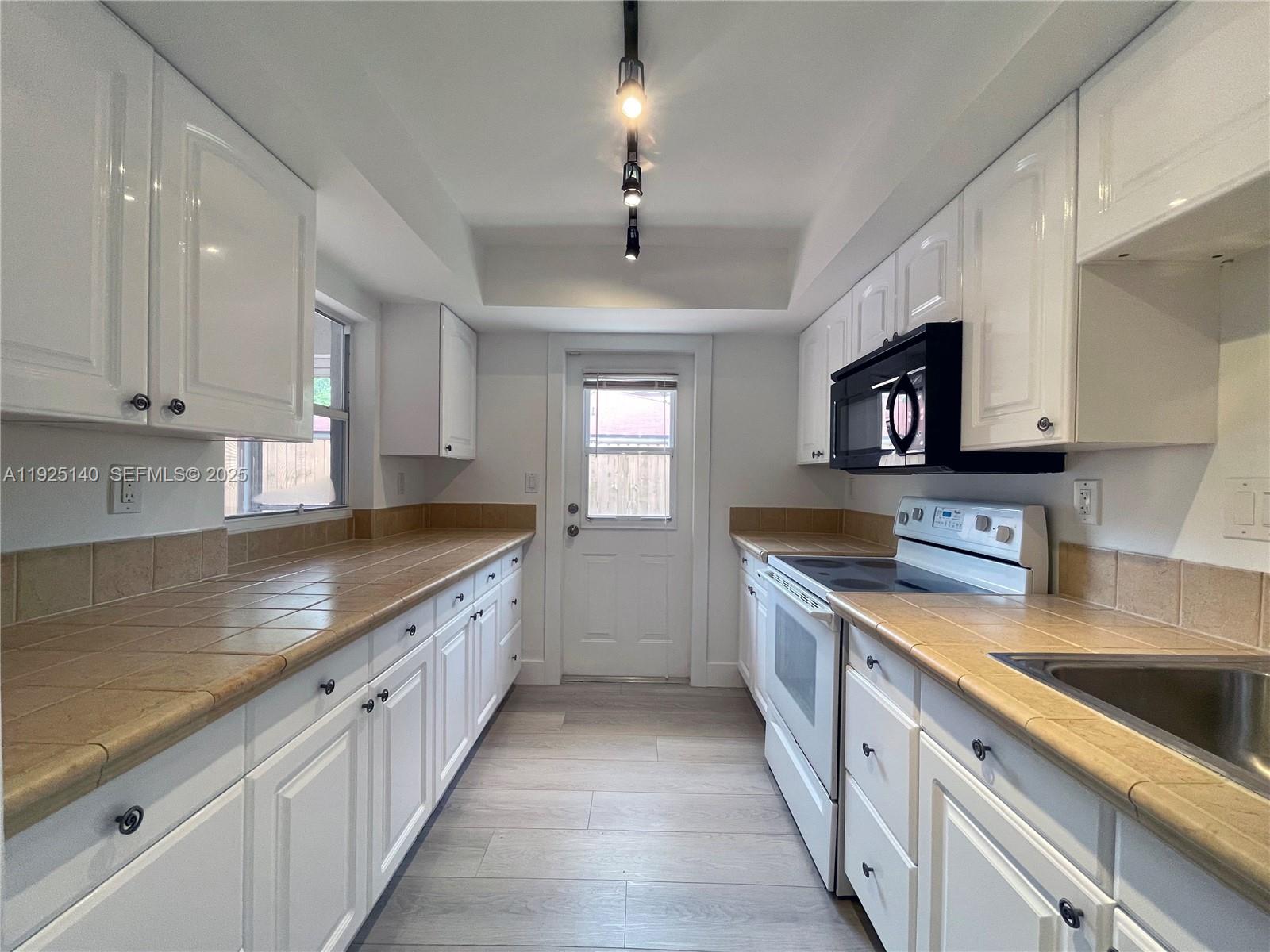 2230 Spanish Trail, Unit A Delray Beach, FL 33483 - Photo 4 of 23 a large kitchen with stainless steel appliances granite countertop a sink a stove top oven a counter space and cabinets