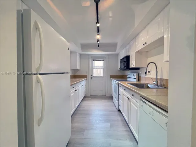 a large kitchen with stainless steel appliances granite countertop a sink and a refrigerator