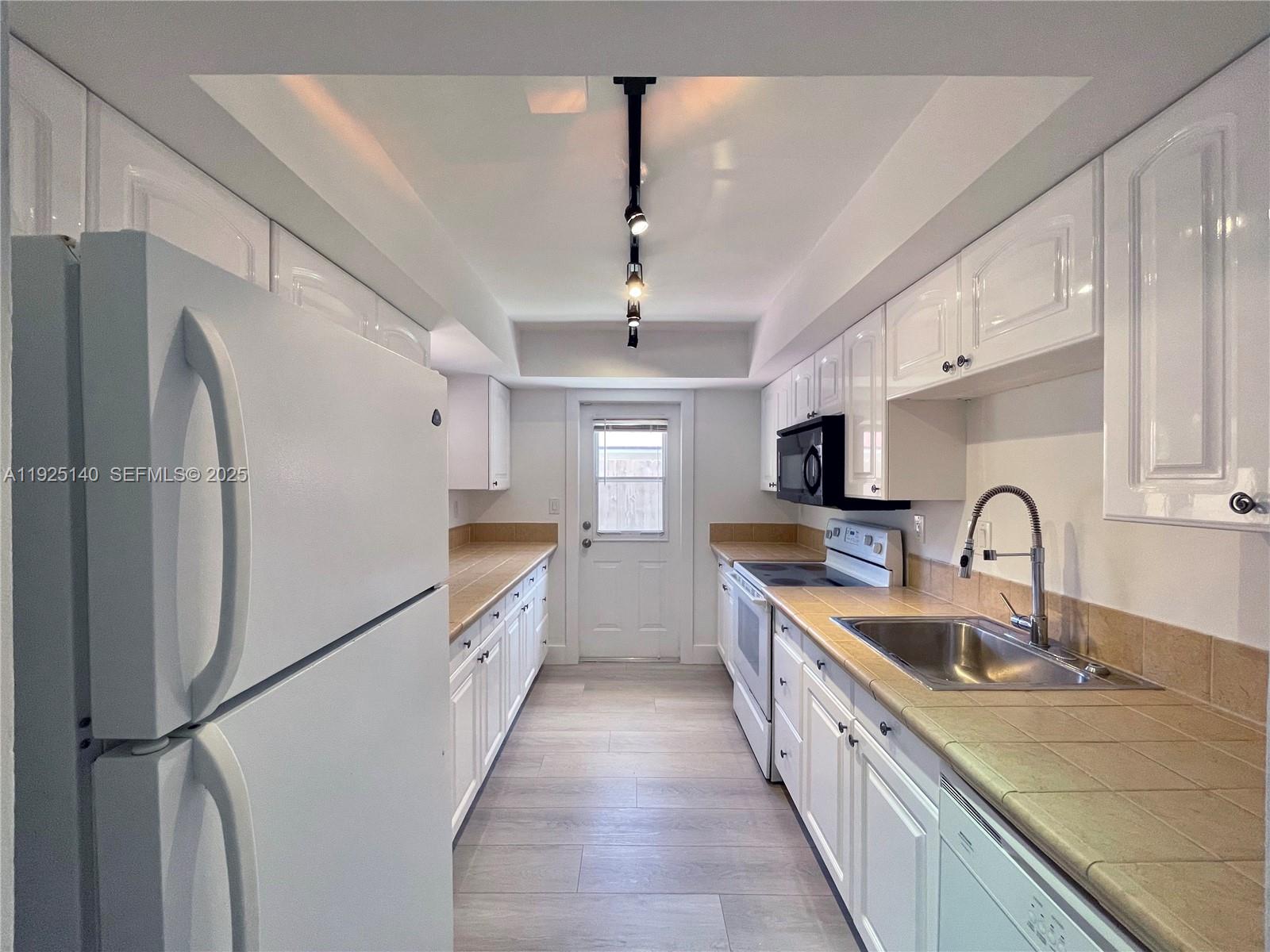 2230 Spanish Trail, Unit A Delray Beach, FL 33483 - Photo 6 of 23 a large kitchen with stainless steel appliances granite countertop a sink refrigerator and cabinets