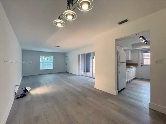 a view of empty room with wooden floor and window