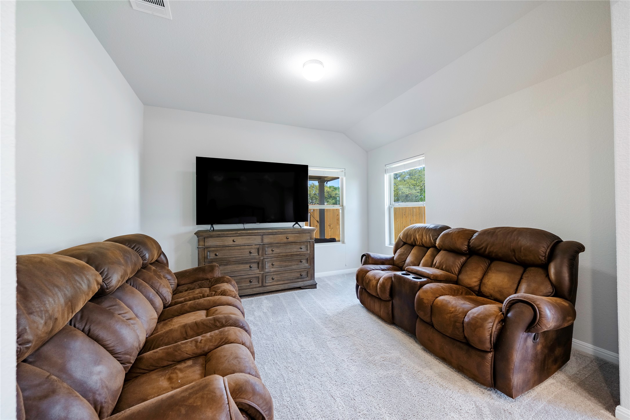 2021 Cartway Court Leander, TX 78641 - Photo 15 of 31 Living room featuring visible vents, light colored carpet, baseboards, and vaulted ceiling