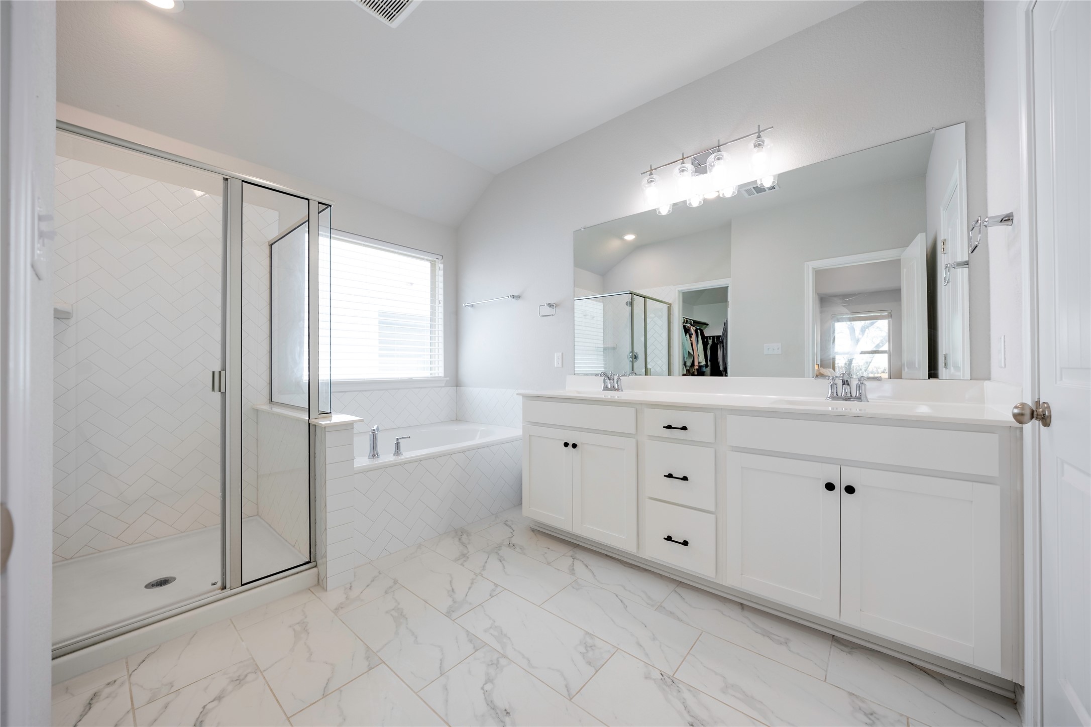 2021 Cartway Court Leander, TX 78641 - Photo 17 of 31 Bathroom featuring a sink, double vanity, vaulted ceiling, a stall shower, and a garden tub