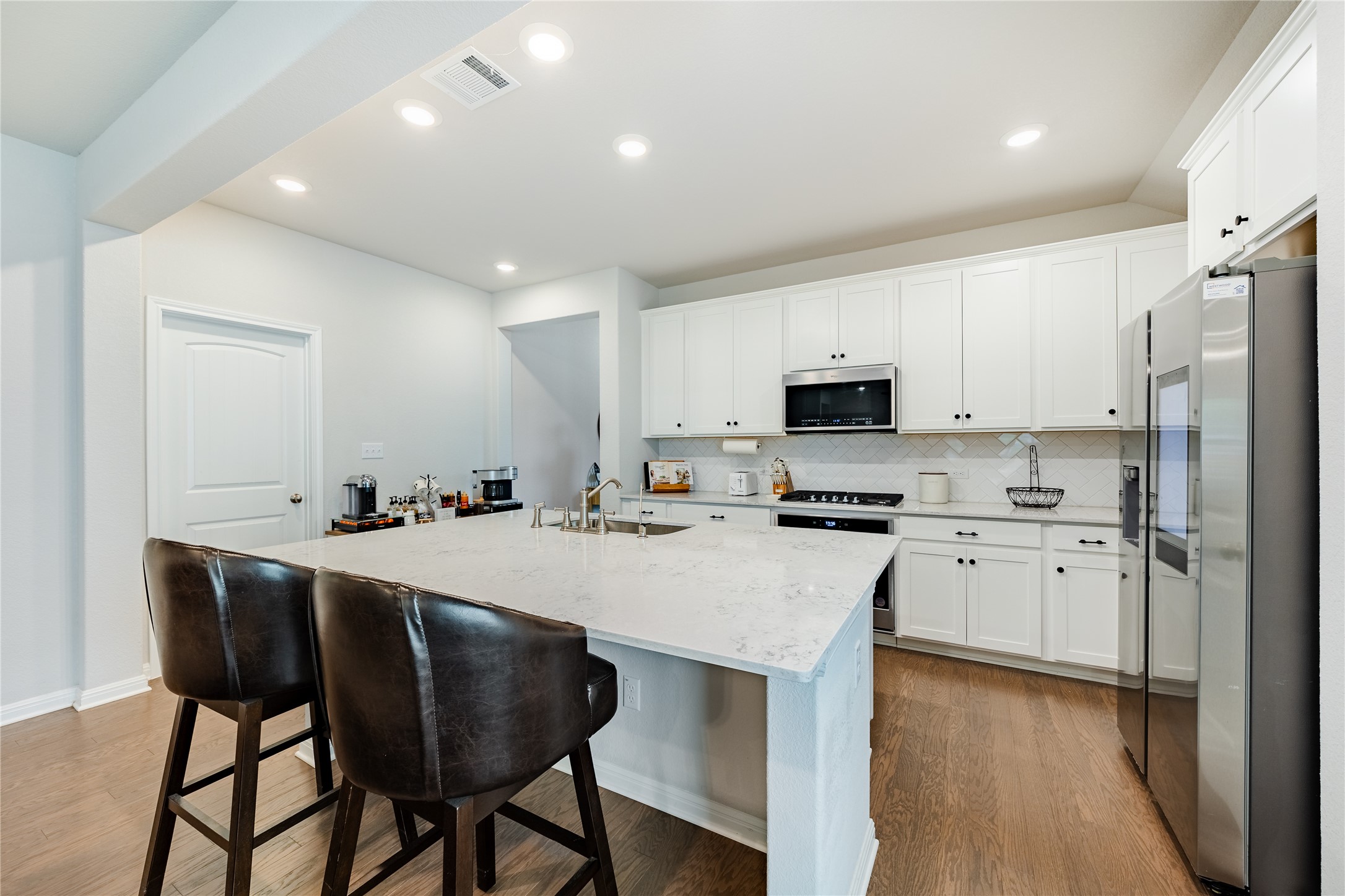 2021 Cartway Court Leander, TX 78641 - Photo 5 of 31 Kitchen with dark wood-type flooring, visible vents, decorative backsplash, stainless steel appliances, and a sink