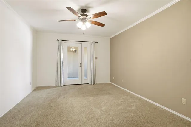 an empty room with a chandelier fan and windows