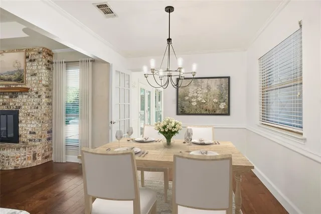 a dining room with wooden floor a chandelier a glass table and chairs