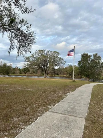 a view of a lake with a yard and large trees