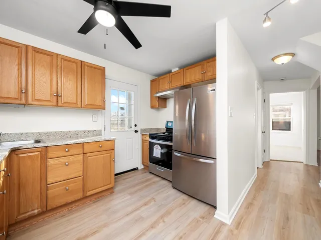 a kitchen with stainless steel appliances granite countertop a refrigerator a stove and a sink with wooden floors