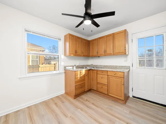 a kitchen with granite countertop wooden floors white cabinets and stainless steel appliances
