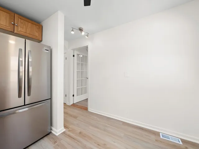 an empty room with wooden floor and a refrigerator