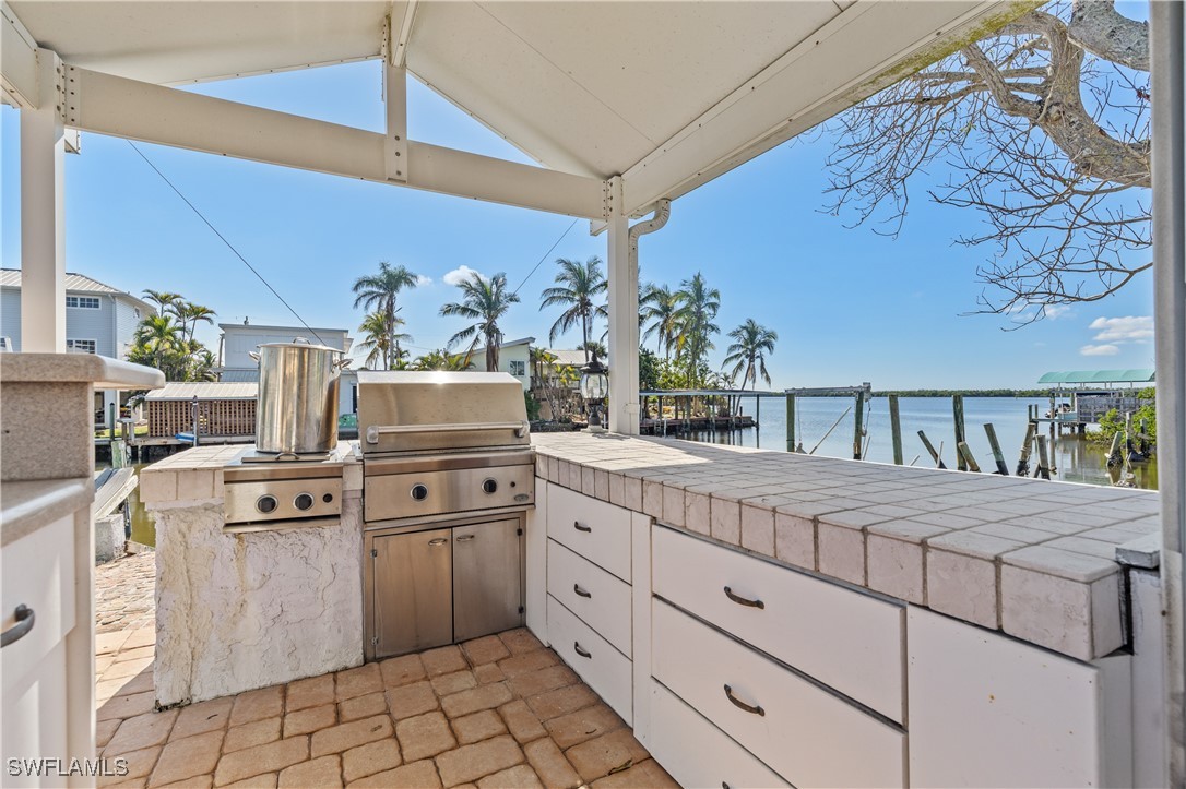 4673 Pine Island Road Matlacha, FL 33993 - Photo 5 of 29 a kitchen with stainless steel appliances a stove a chimney a dining table and chairs