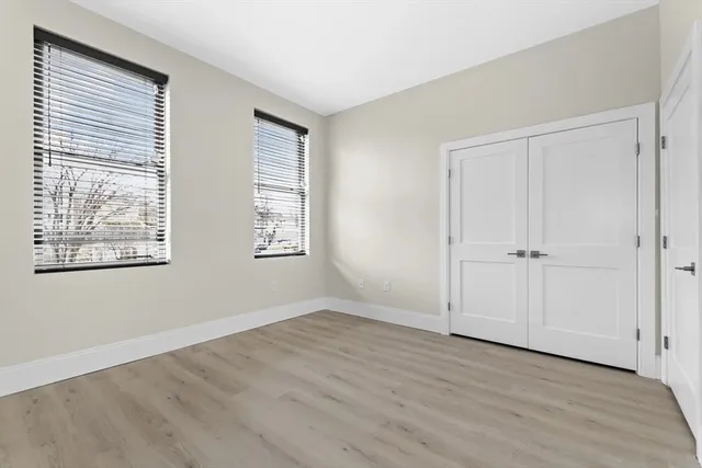 an empty room with wooden floor and windows