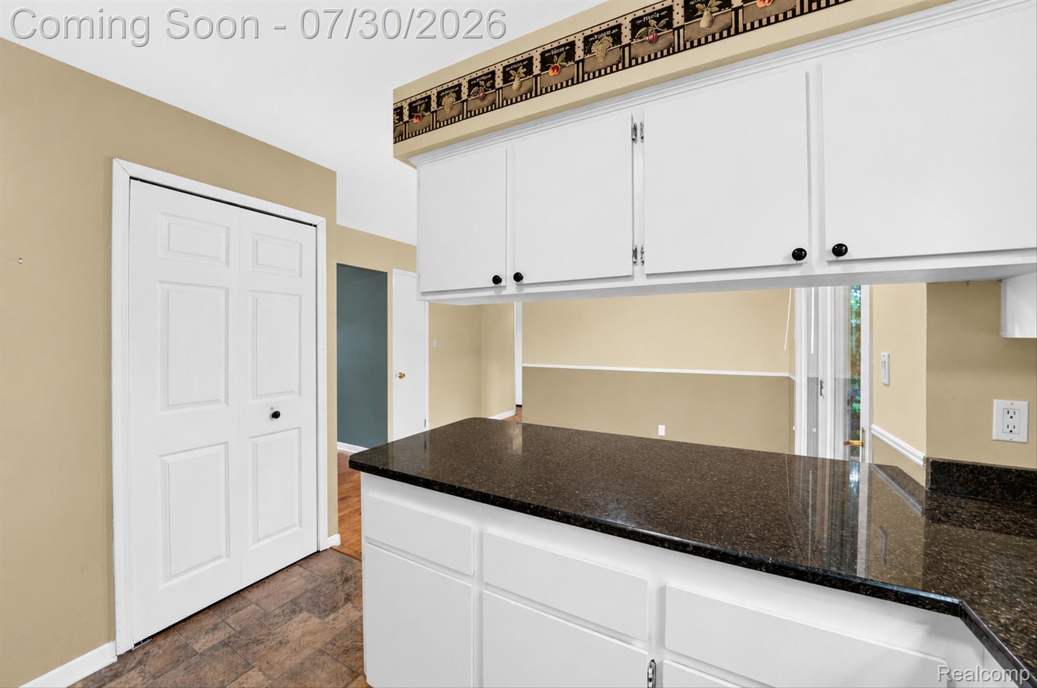 5991 Maybee Road Clarkston, MI 48346 - Photo 10 of 41 Kitchen pass-through featuring dark speckled countertops and white cabinetry