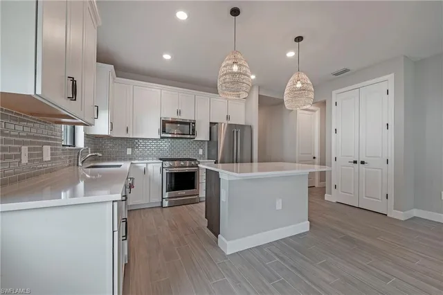 a large kitchen with granite countertop a large counter top a sink stainless steel appliances and cabinets