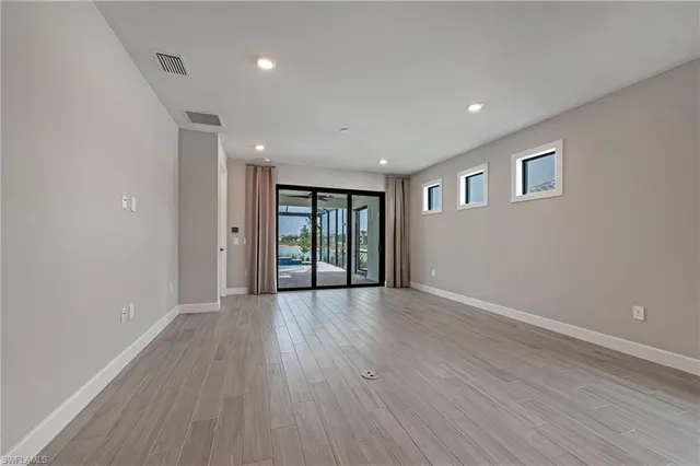 a view of an empty room with wooden floor and windows