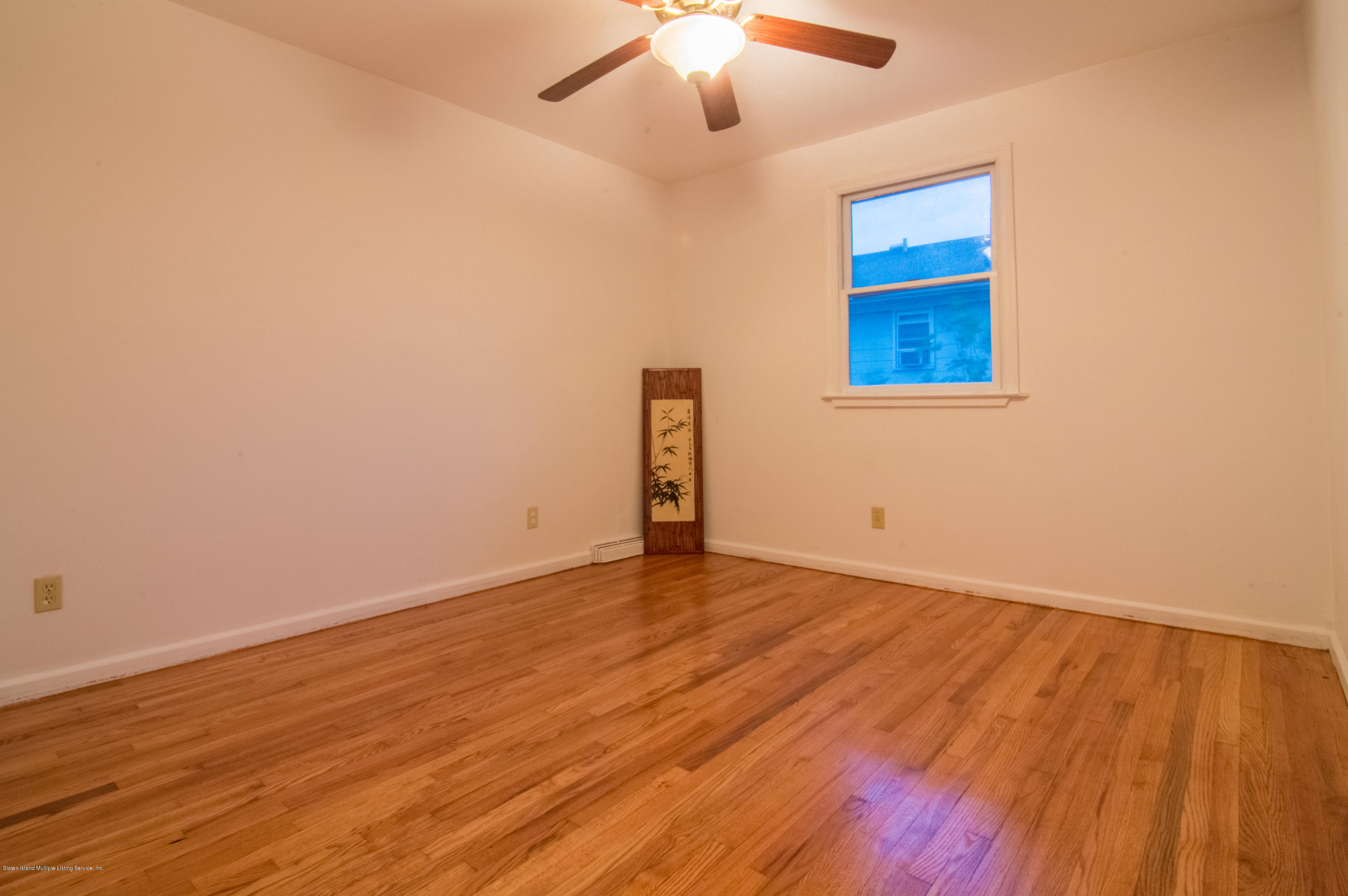 3298 Amboy Road Staten Island, NY 10306 - Photo 9 of 16 wooden floor in an empty room with a window