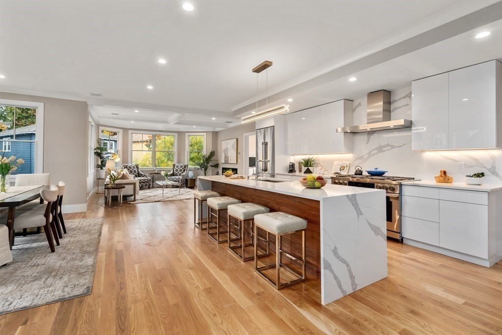 a living room with stainless steel appliances granite countertop furniture wooden floor and a kitchen view