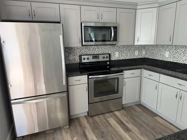 a kitchen with white cabinets and stainless steel appliances