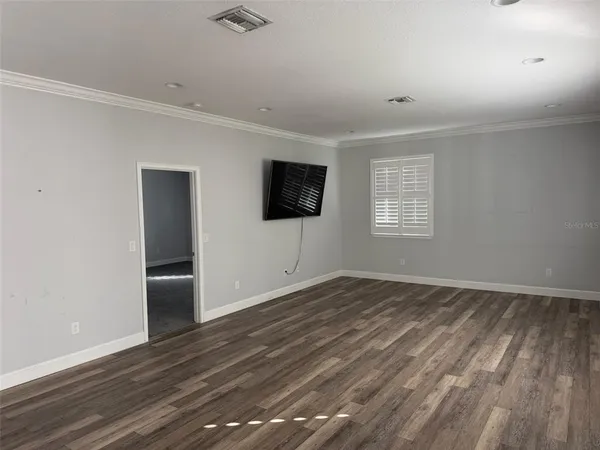a view of an empty room with a window and wooden floor