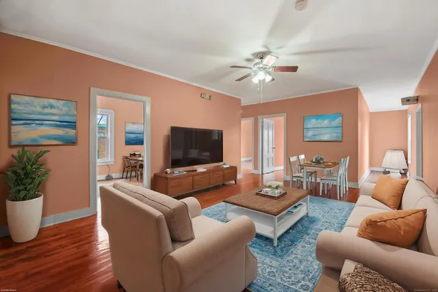 a living room with furniture a flat screen tv and wooden floor