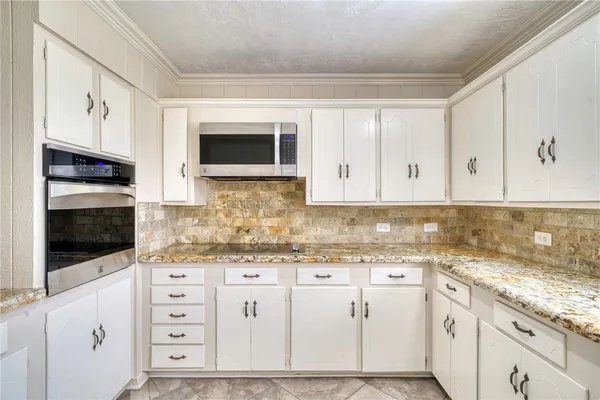 a kitchen with granite countertop white cabinets and stainless steel appliances