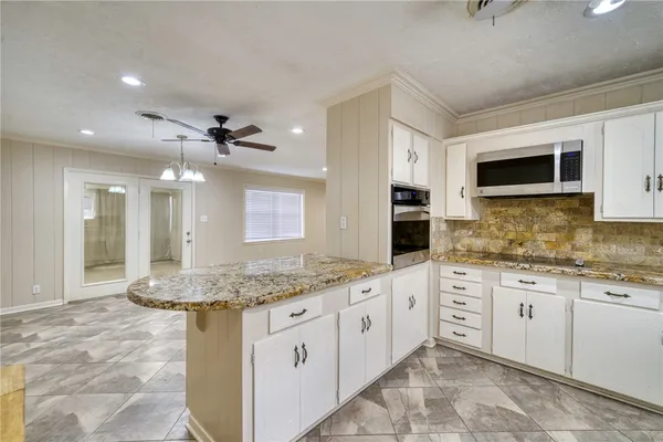 a kitchen with granite countertop a sink stainless steel appliances and white cabinets