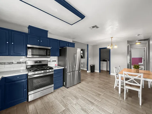 a kitchen with stainless steel appliances wooden floor and a refrigerator