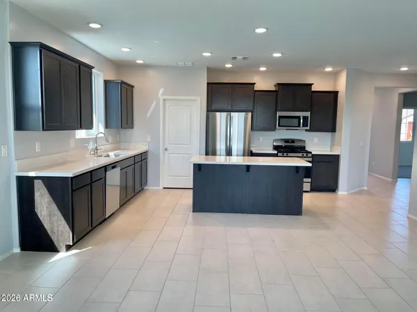 a large kitchen with stainless steel appliances granite countertop a large counter top a stove a sink and a refrigerator