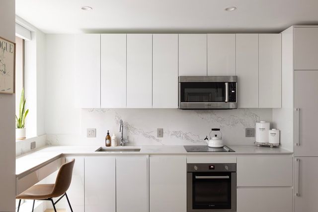 a kitchen with granite countertop white cabinets and stainless steel appliances