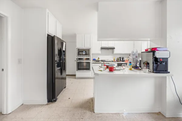 a living room with stainless steel appliances a refrigerator a stove and a refrigerator