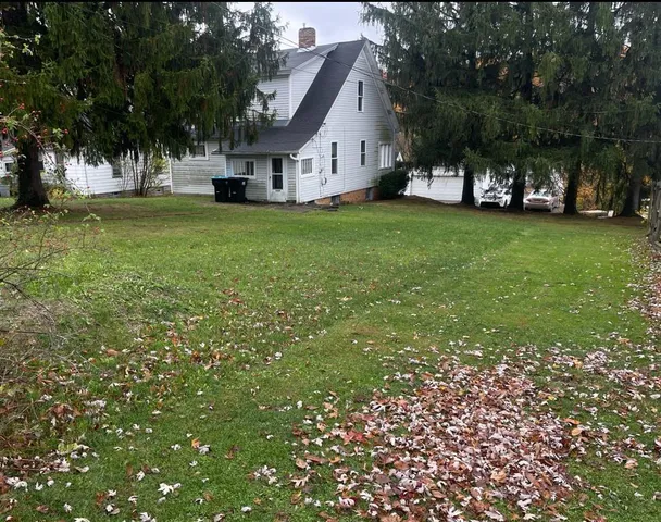 a view of a house with a big yard and large trees