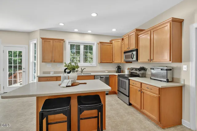 a large kitchen with stainless steel appliances kitchen island granite countertop a sink and cabinets